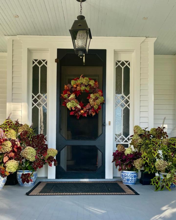Burgundy hydrangea wreath from @oldhouse1908. Moody autumn entry with matching porch planters.