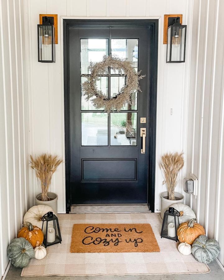 Neutral wheat wreath entryway from @the_hoffman_homestead. Fall front door decor ideas with pumpkins and lanterns.