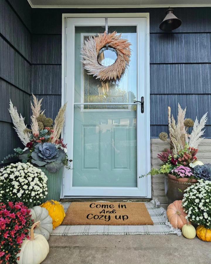 Pampas wreath front door from @lifegardenstyle. Layered pumpkins, mums, and textured fall planters welcome guests.