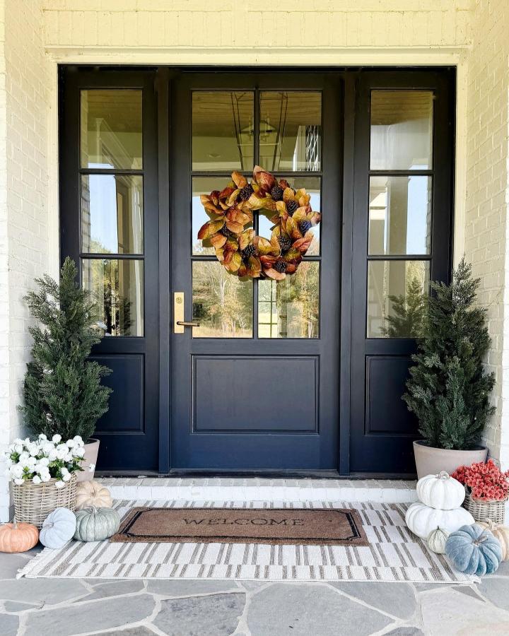 Rustic autumn wreath front door from @rachellorrainehome. Navy entry with pumpkins, greenery, and layered rugs.
