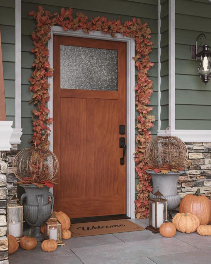 Russet leaf garland front door from @masonitedoors. Wire pumpkins and warm fall accents frame the entry.