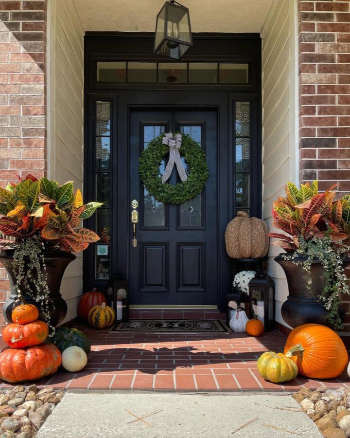 Greenery wreath front door from @asouthernflare. Croton planters and colorful pumpkins create a welcoming autumn entry.