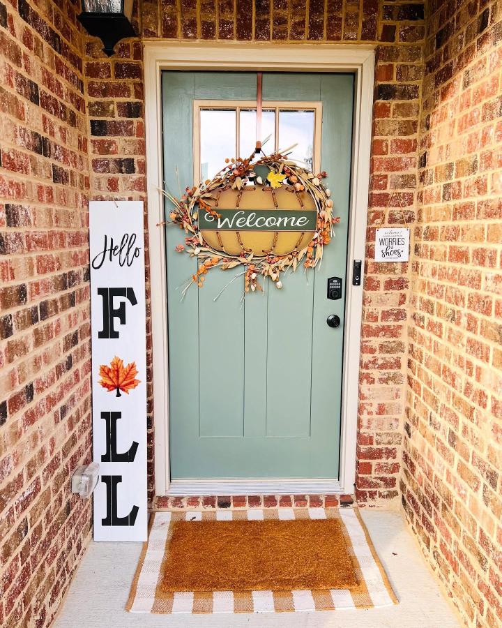 Sage green front door from @leahandkodesigns. Harvest wreath, Fall sign, and checked doormat welcome guests.