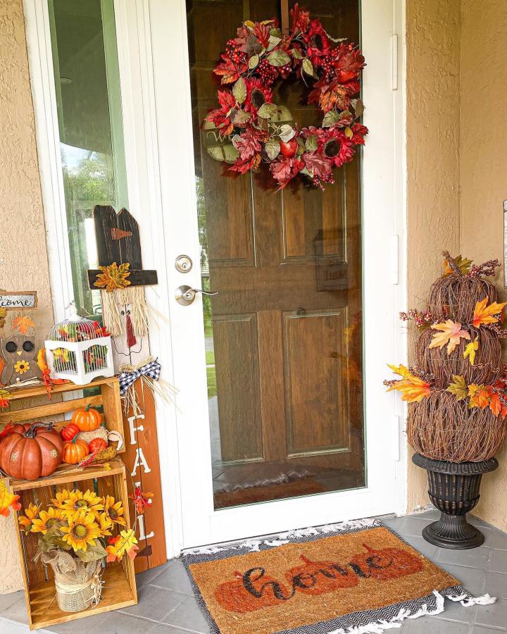 Burgundy harvest wreath and pumpkin display from @anyreasontoparty. Welcoming autumn front steps with layered seasonal accents.