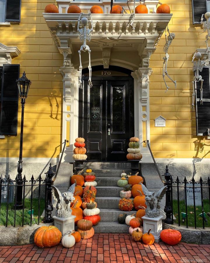Orange and ivory pumpkin stairs from @purelysalem. Dramatic fall front steps decor ideas with skeletons and black railings.