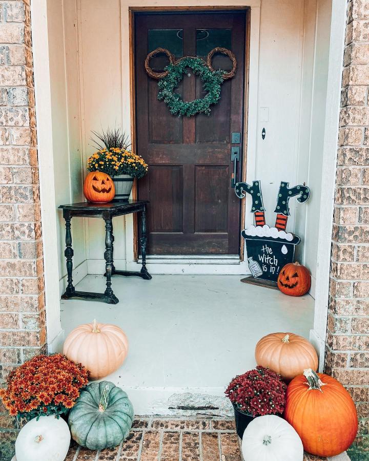 Dark brown fall entryway from @sydneyspakes. Pumpkins, mums, wreath, and witch sign decorate the front steps.