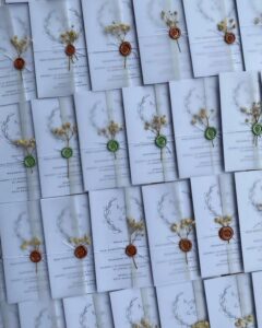 Soft gray vellum wedding invitations from @wishess.my. Rust wax seals, dried yellow flowers, and botanical sketches.