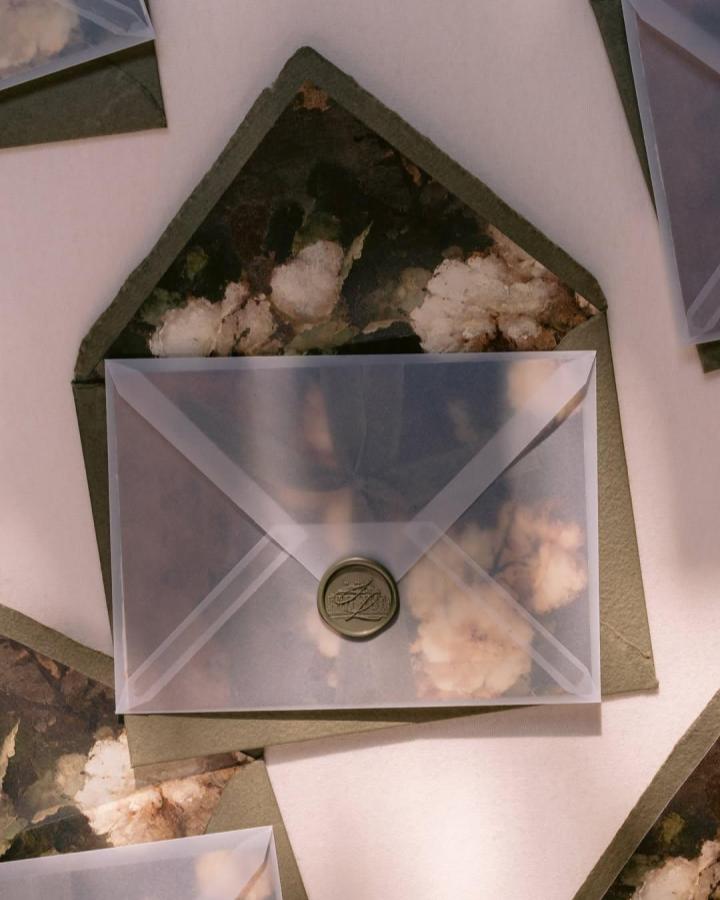 Translucent vellum envelope from @papiradesign. Olive green floral paper and a round wax seal create a tactile invitation suite.