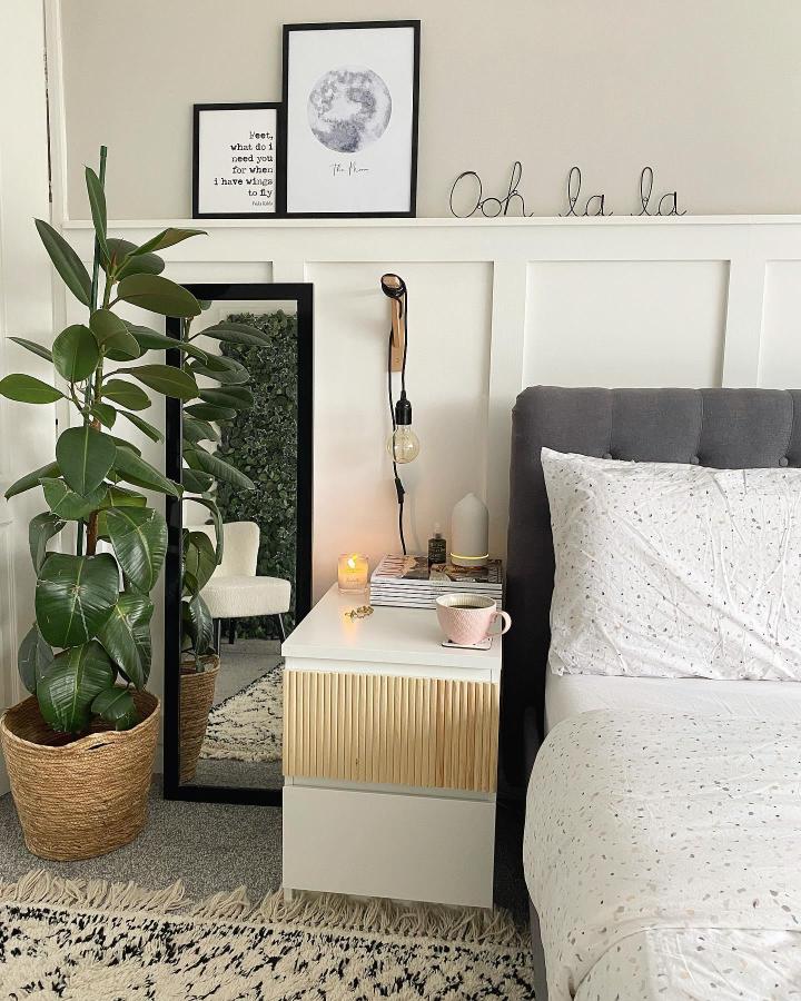White and natural wood bedroom nightstand from @thebohoabode5. Ribbed drawer front beside a charcoal bed.