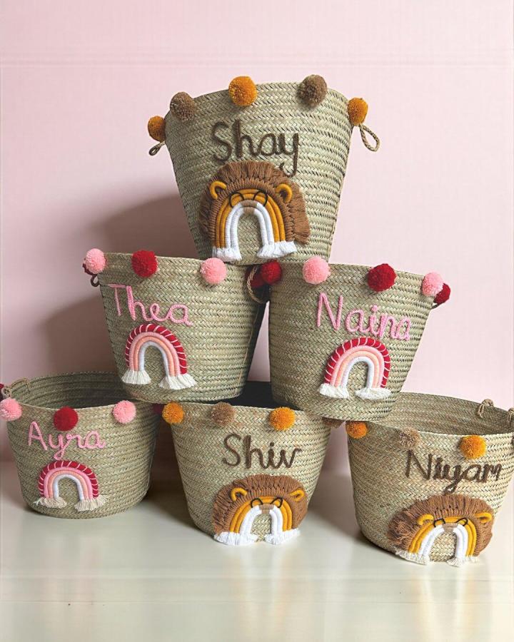 Natural woven macrame baskets from @woven.ke. Rainbow trims, pom-poms, and personalized names create playful animal-inspired storage.