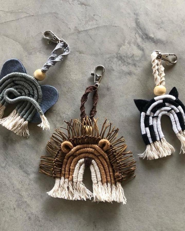 Earthy brown and cream macrame animal keychains from @waxbill_and_i. Fringed faces with wooden beads and metal clasps.