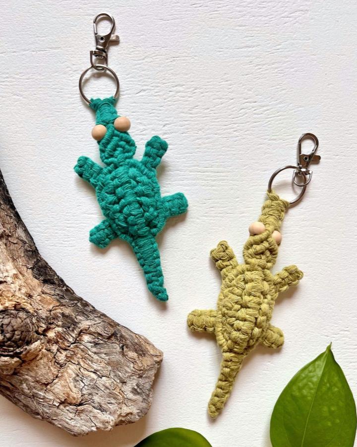 Turquoise and olive green macrame lizard keychains from @hangmeupmacrame. Textured cotton knots, wooden beads, and silver clasps.
