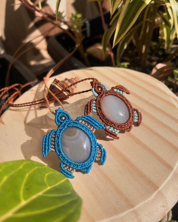 Blue and brown macrame animal pendants from @rootsandreia. Smooth oval stones form charming turtle-like centers.
