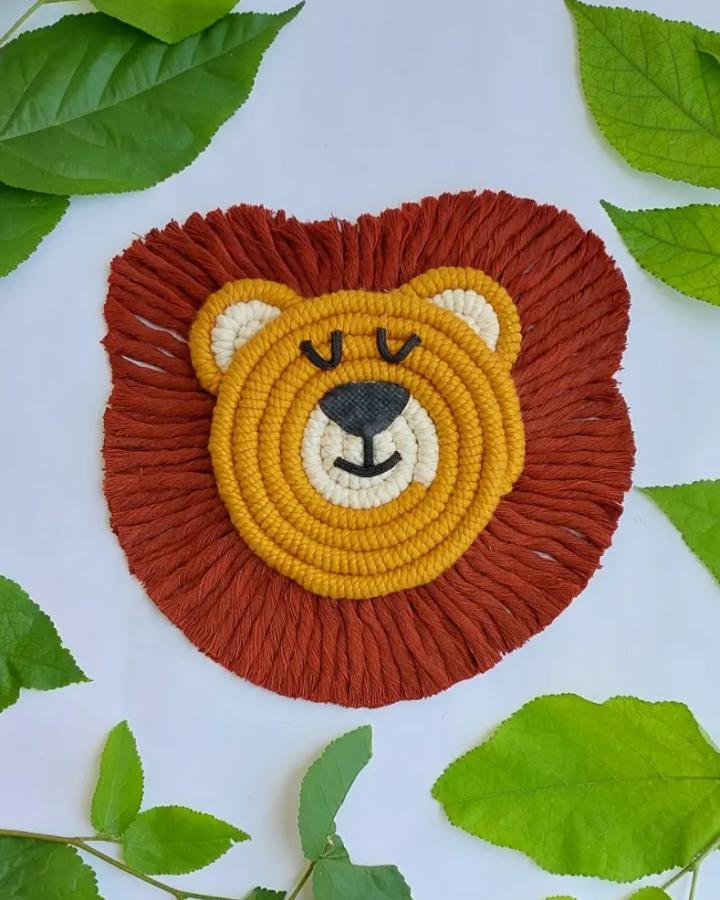 Mustard yellow and rust red macrame lion wall hanging from @sheknotsmacrame. Cream muzzle, sleepy eyes, and fluffy fringe.