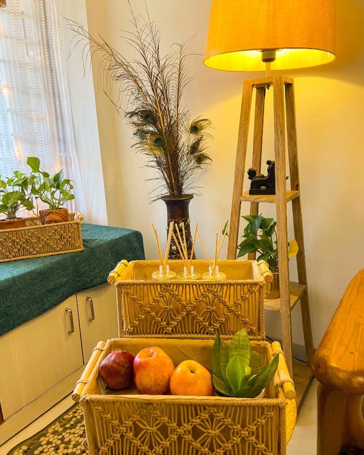 Golden geometric macrame basket display from @_home.decor.ideas_. Tiered baskets hold fruit beside a cozy sofa.