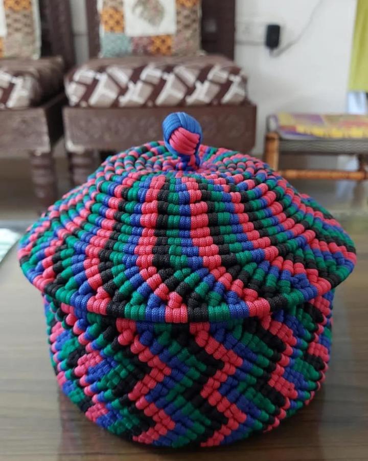 Multicolored woven macrame basket from @_dazzwhite. Round lidded design with bold patterned cord.