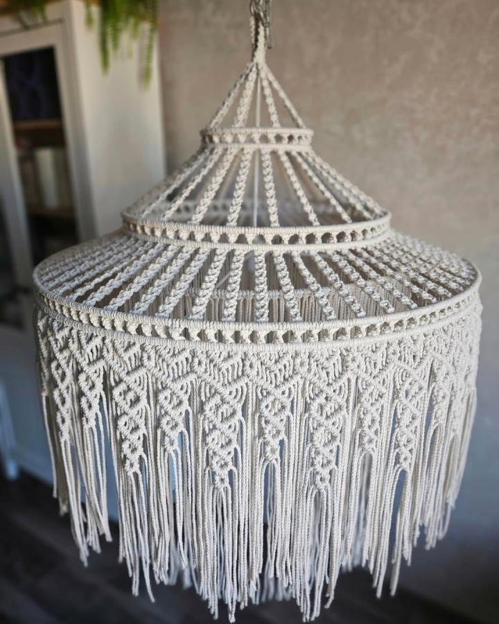 Ivory layered macrame chandelier from @katerina_macrame. Intricate knots and flowing fringe create a soft bohemian fixture.