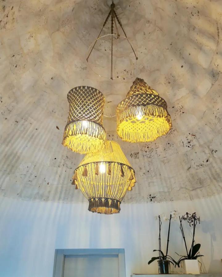 Golden-yellow layered macrame chandelier from @macrameandstuff. Fringe shades glow warmly beneath a textured ceiling.