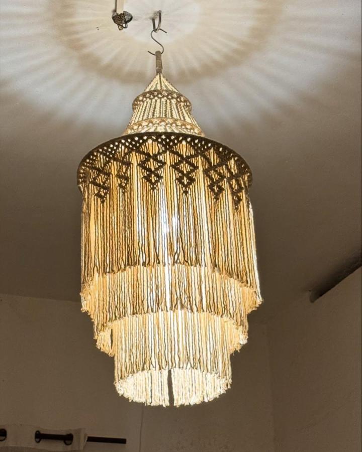 Cream layered macrame chandelier ideas from @mammas_knots. Tiered fringe glows warmly overhead.