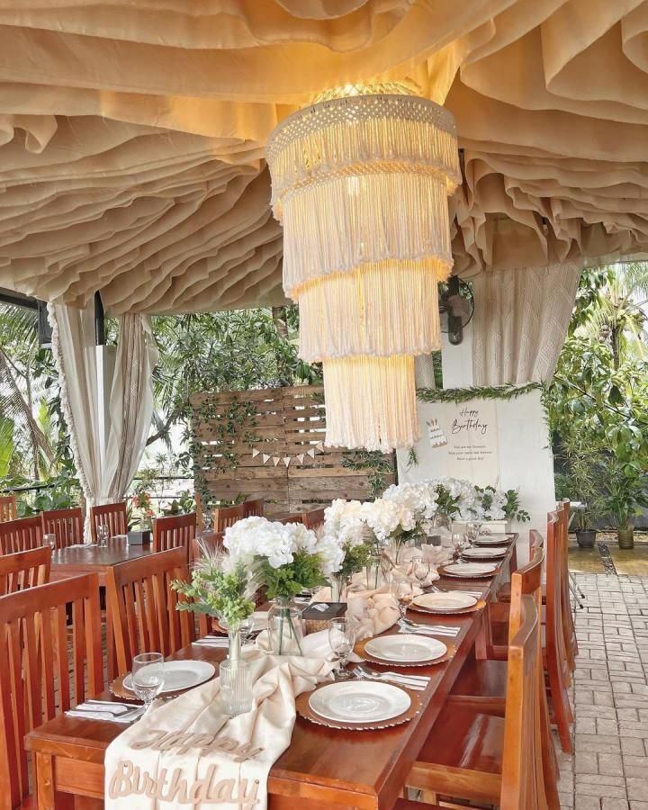 Cream layered outdoor dining macrame chandelier ideas from @knottingelle. Tiered fringe glows above a festive table.
