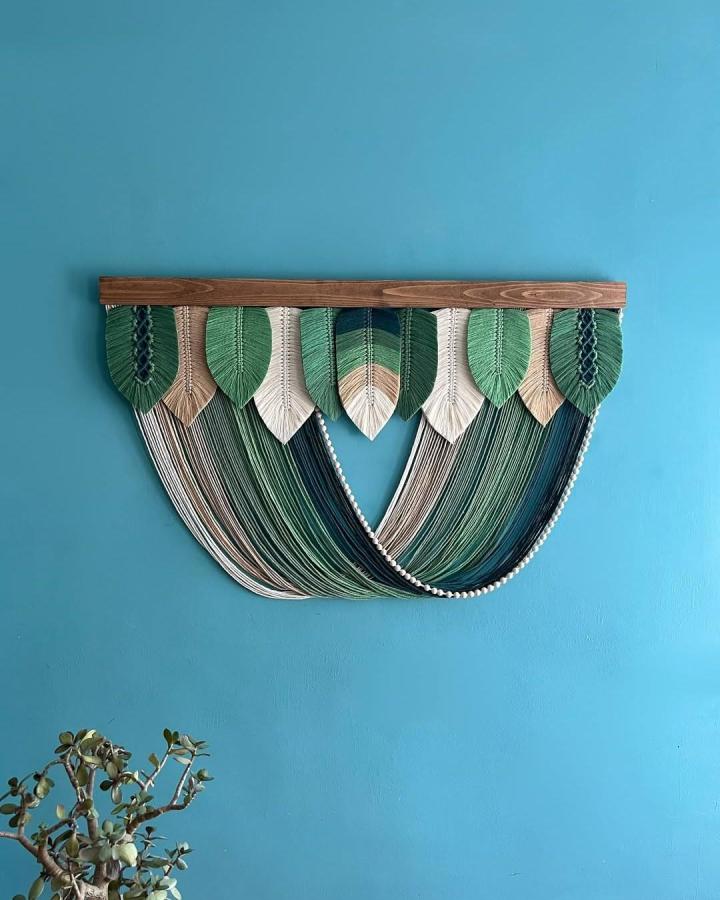 Green and cream macrame decor ideas wall hanging from @kowli_crafts. Layered leaf shapes and flowing fringe.