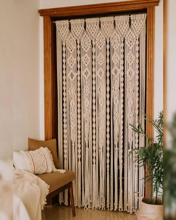 Cream Framed Macrame Doorway Curtain from @tassels.eg. Intricate knots and tassels soften a cozy seating corner.