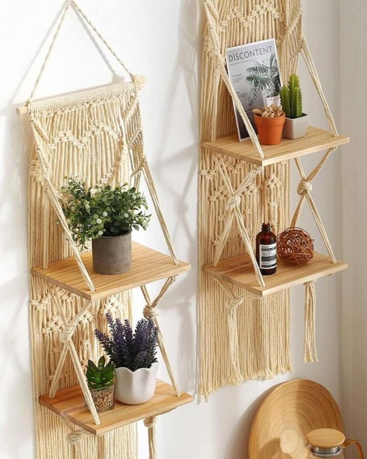 Cream macrame wall shelves from @mossonlineretail. Layered wood ledges hold plants and decor.
