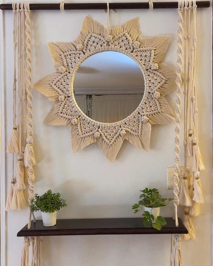 Cream sunburst macrame mirror from @macrame_by_doaa. Fringed knots brighten a plant shelf.