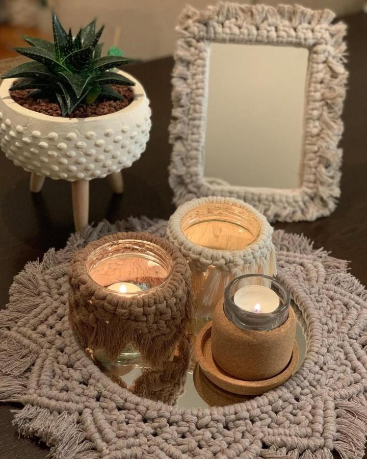 Cream macrame decor ideas display from @esreciks_coffee_cactus. Textured mirror, candles, planter, and woven mat.