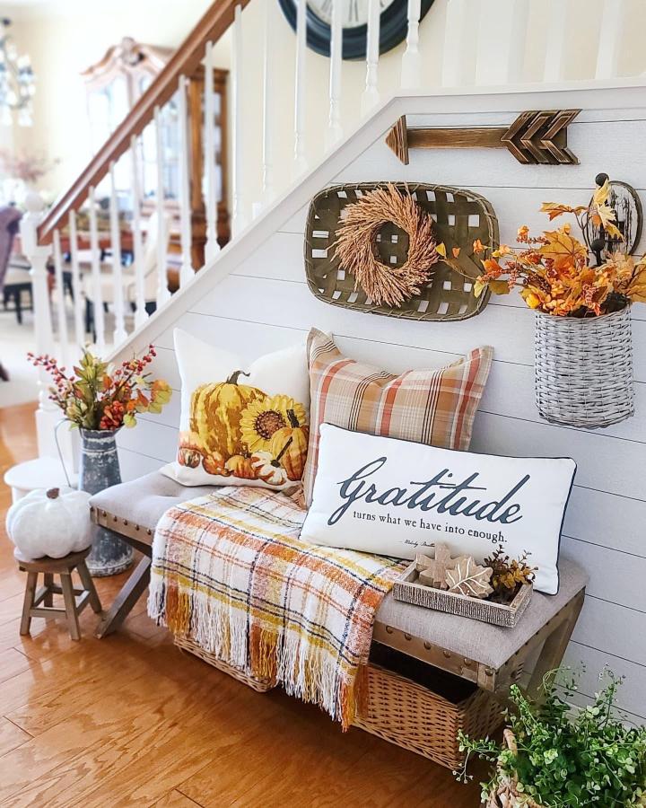 Warm plaid outdoor bench from @simple.joy.at.home. Basket greenery and pumpkins create a welcoming autumn entry.
