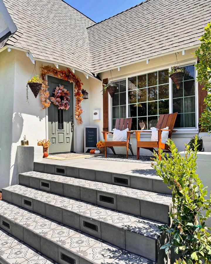 Rust orange garland front porch from @reedsindeed. Layered doorway, hanging baskets, and patterned steps welcome autumn guests.