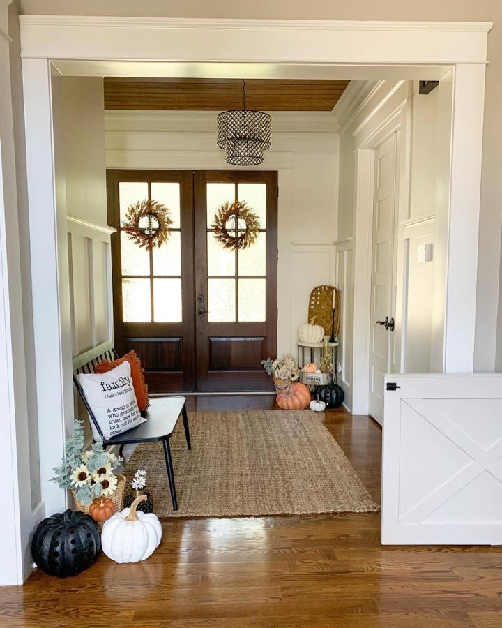 Natural autumn entryway from @mygeorgiahouse. Wreaths, pumpkins, bench, and woven textures welcome guests.
