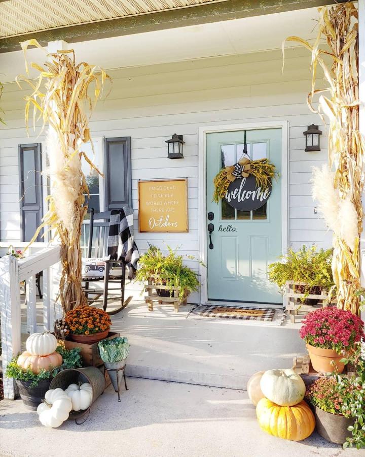 Golden cornstalk porch from @fallons.homestead. outdoor fall decor ideas with pumpkins, mums, and pale blue door.