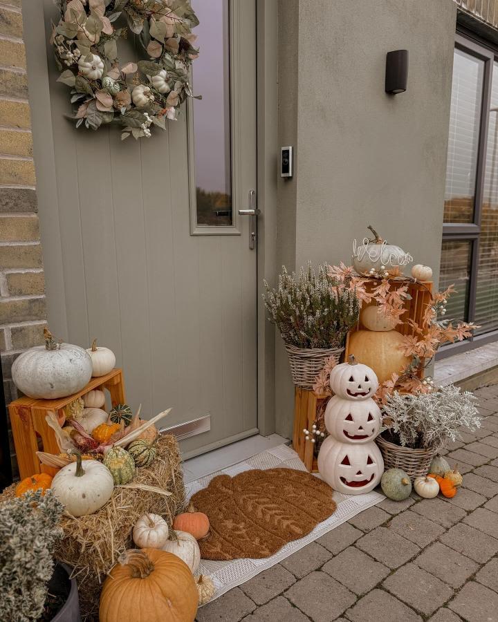 Muted sage-gray door with cream pumpkins and woven crates from @natster9. Layered harvest accents brighten a compact entry.