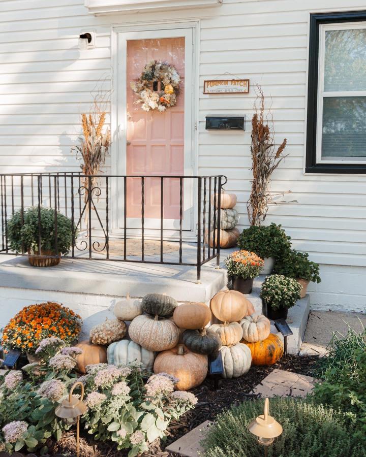 Muted pumpkin and floral porch from @emilywelchstyle. Compact autumn entry with layered gourds and mums.
