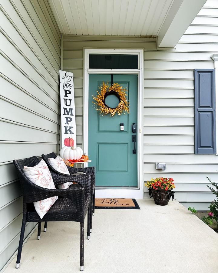 Teal and golden pumpkin porch decor from @eleanor_decor. Compact entry with wicker chairs and autumn accents.