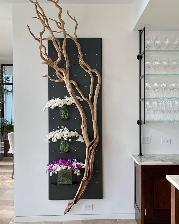 Natural tan tree branch decor crafts wall display from @artefactcura. White and purple flowers accent black backing.