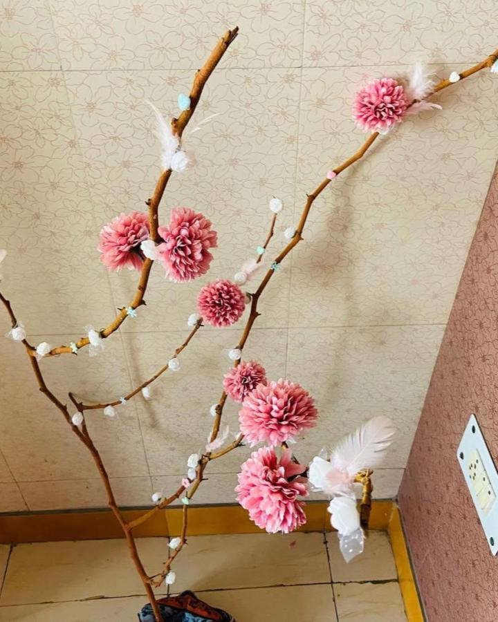 Pink floral branch arrangement from @diywithsanya. Natural branches decorated with blossoms, feathers, and pastel accents.