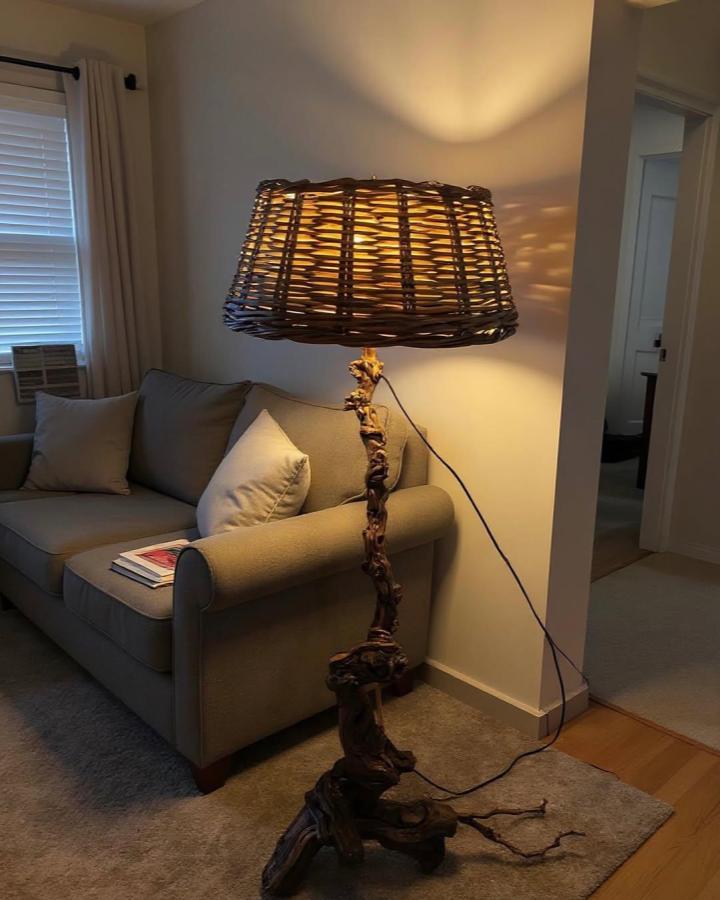Warm amber woven branch floor lamp from @overlook.tr. Living room lighting casts leafy shadows.
