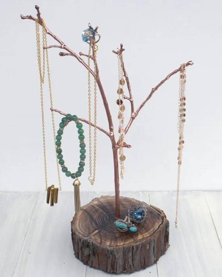 Natural Branch Jewelry Display from @resincraftsblogbyeti. Green beads and necklaces hang from a rustic wood slice.