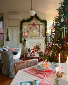 Apartment christmas decor ideas featuring a garland-framed mirror, glowing mantel, decorated tree, and festive dining table.