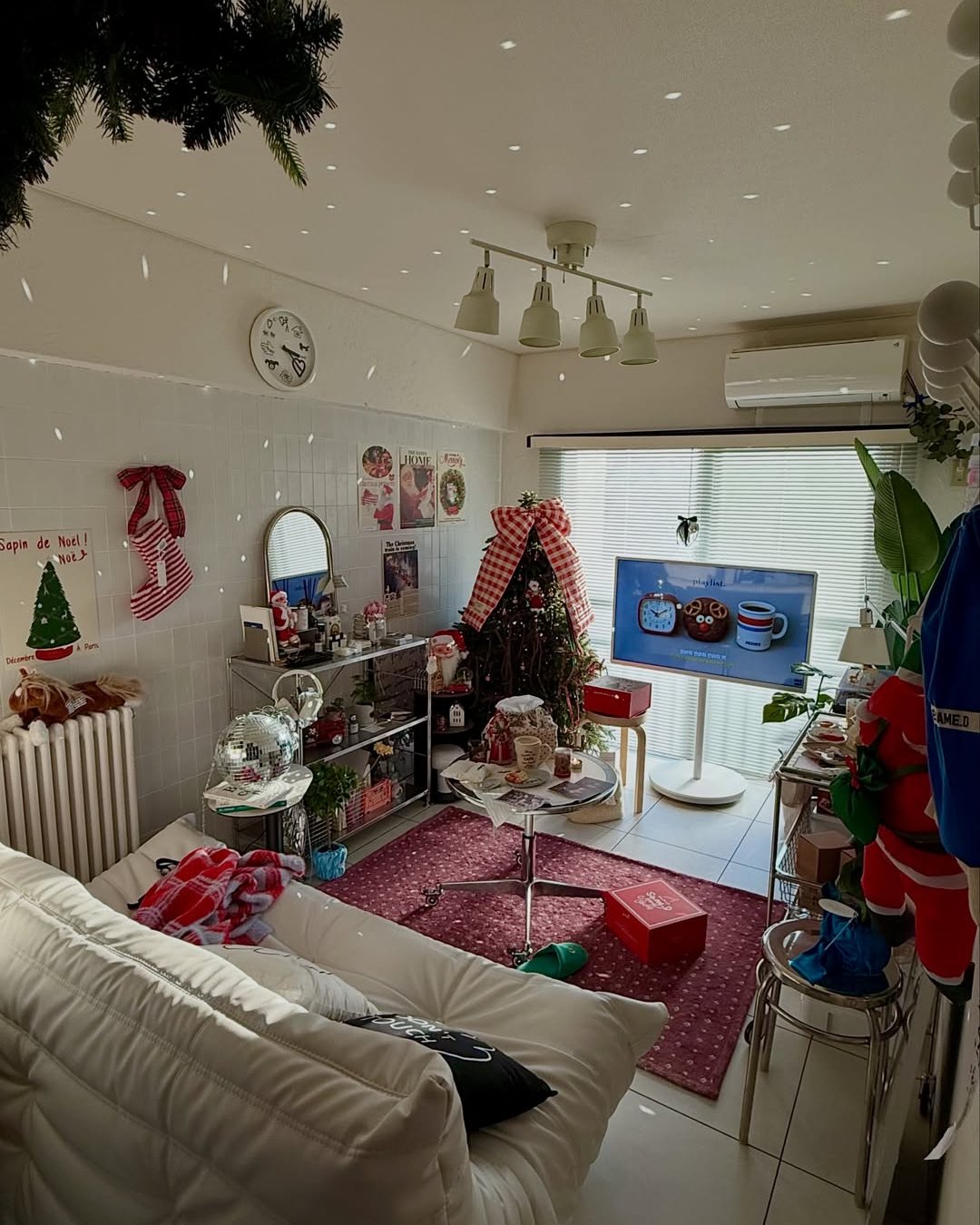 Cozy apartment Christmas living room with gingham bows, tree, stockings, and festive red accents