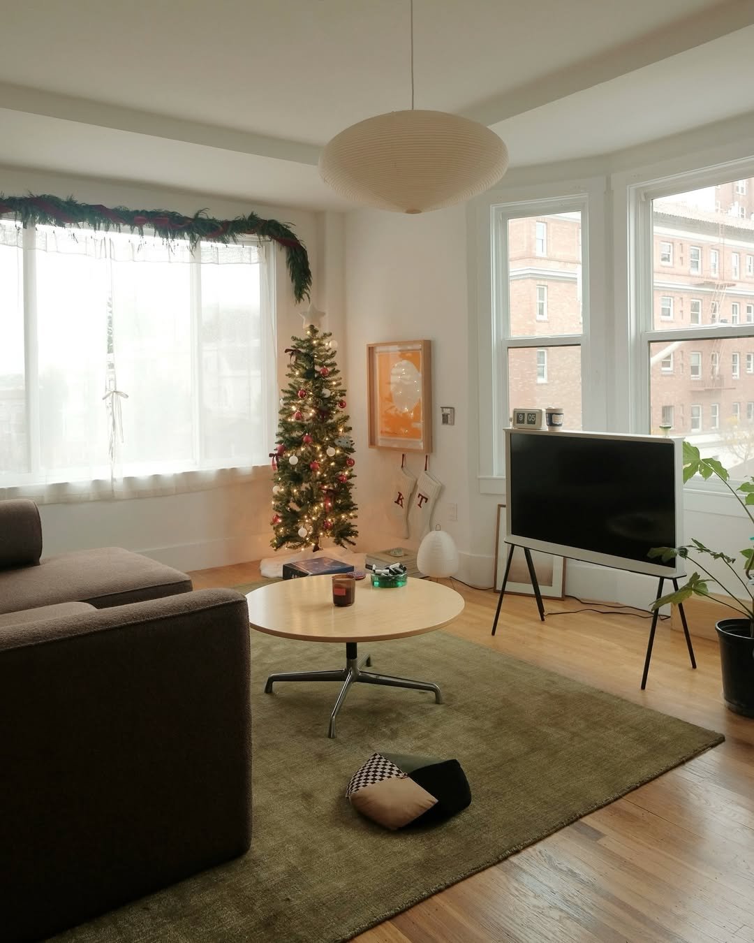 Apartment living room with a glowing Christmas tree and garland-framed windows