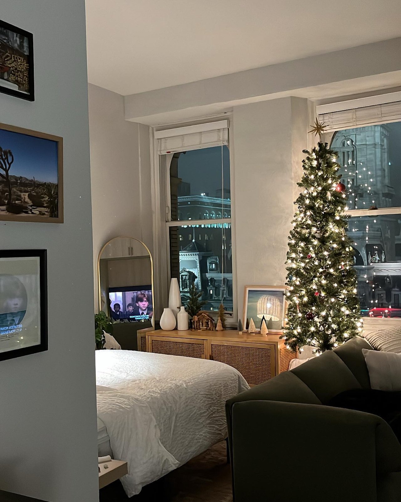 Slim Christmas tree with warm lights, red ornaments, and natural apartment living room decor