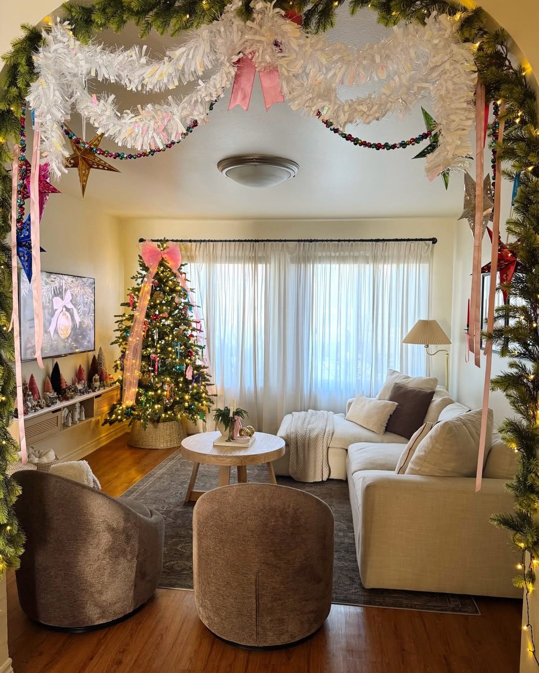 White tinsel garlands and glowing Christmas tree frame a cozy apartment living room