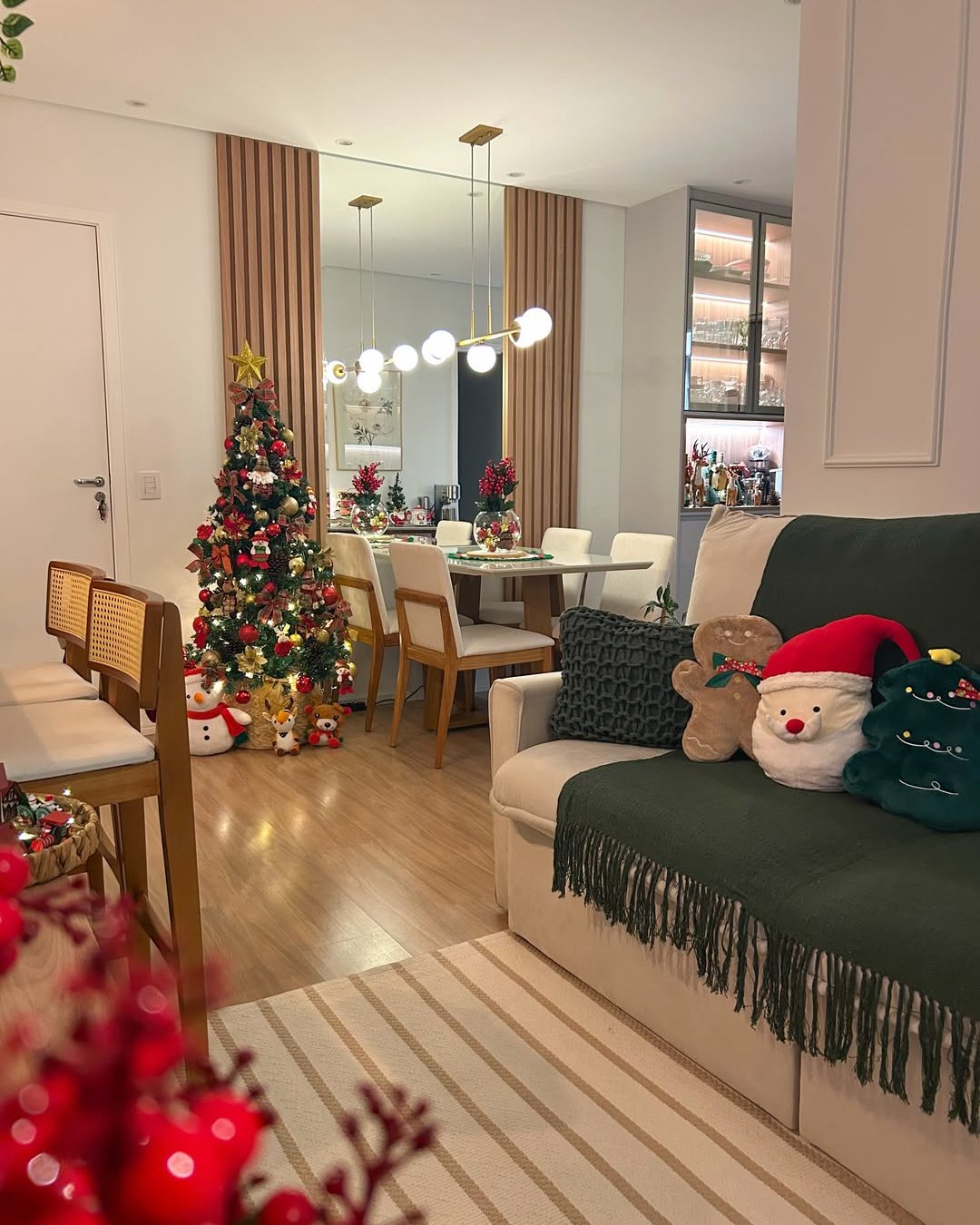 Apartment christmas decor ideas featuring a decorated tree, festive sofa cushions, green throw, and dining table accents