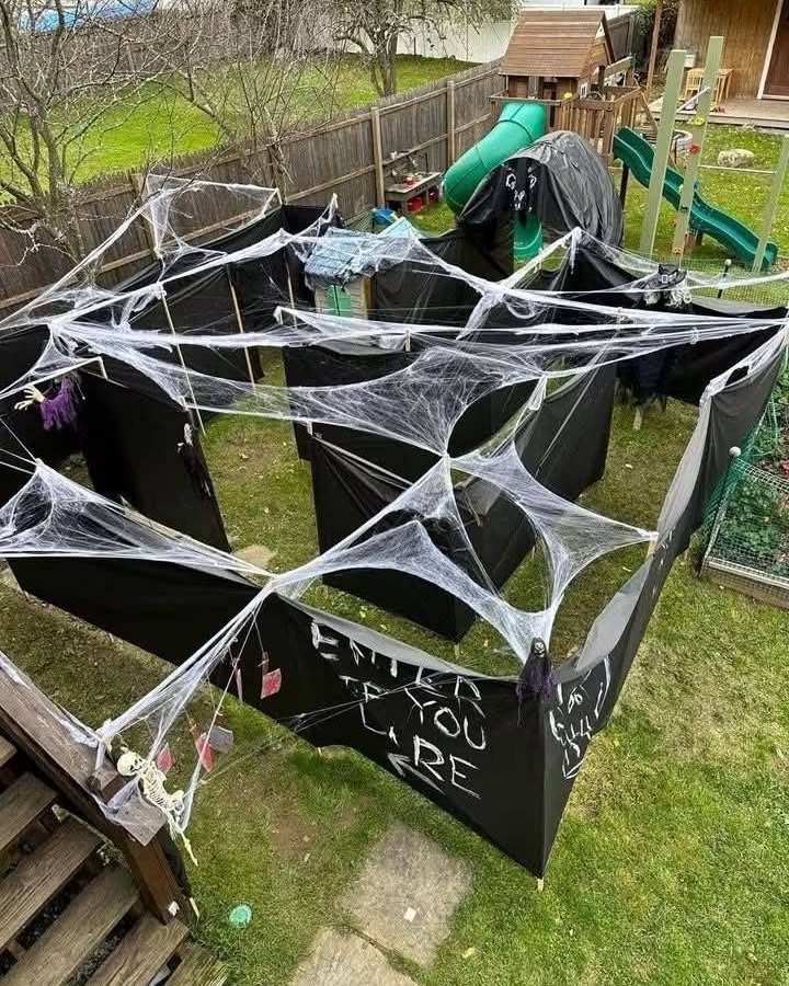Black fabric maze with spider webs and skeleton accents for backyard halloween party ideas