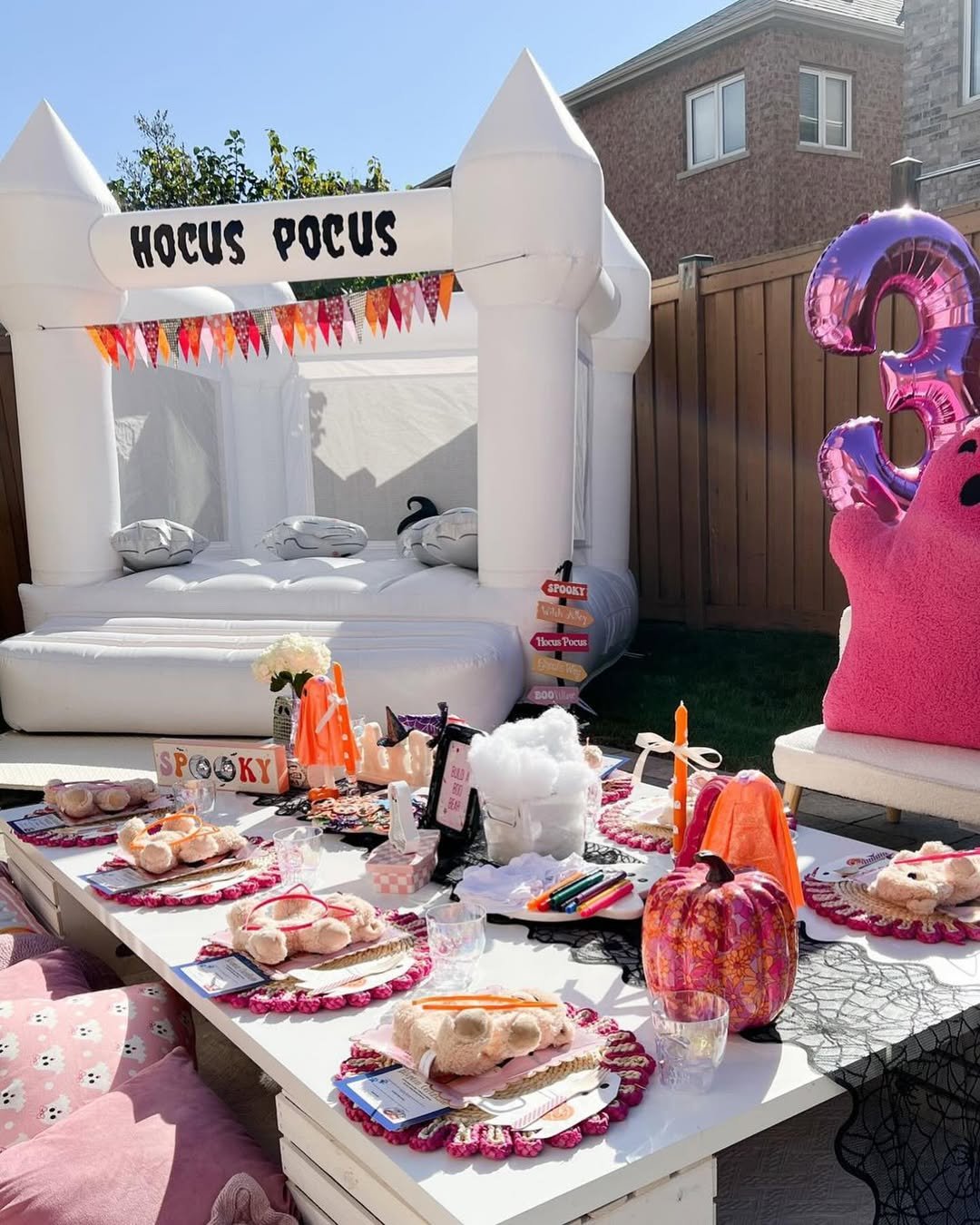 White Hocus Pocus inflatable playhouse beside a decorated table for a cheerful outdoor Halloween celebration