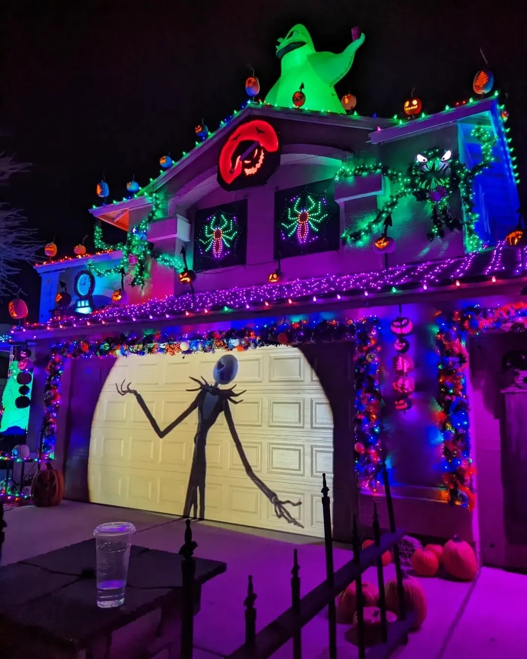 Spooky neon-lit home with pumpkins and ghost decorations for an outdoor Halloween celebration