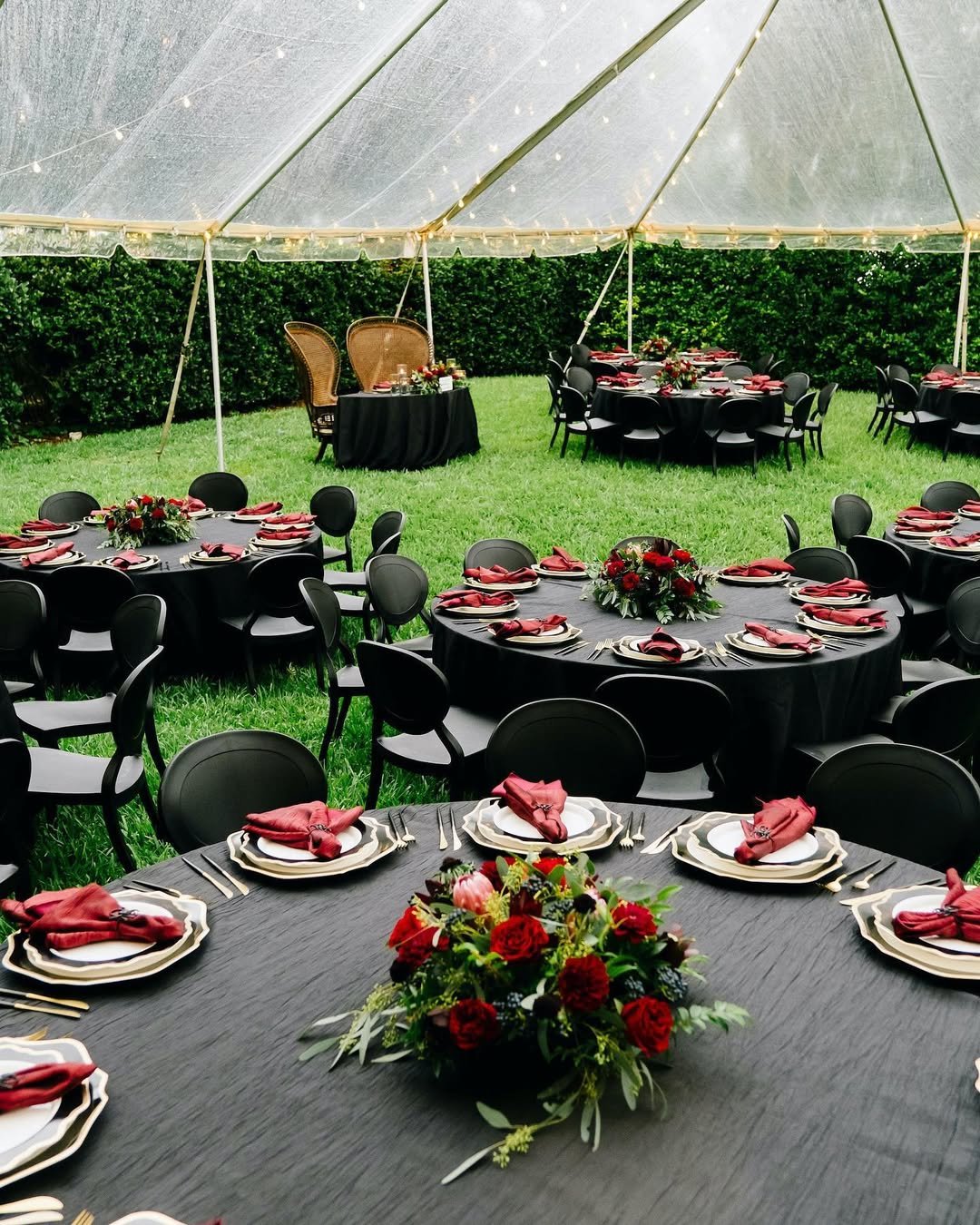 backyard halloween party ideas with black tables, red napkins, floral centerpieces, and string lights